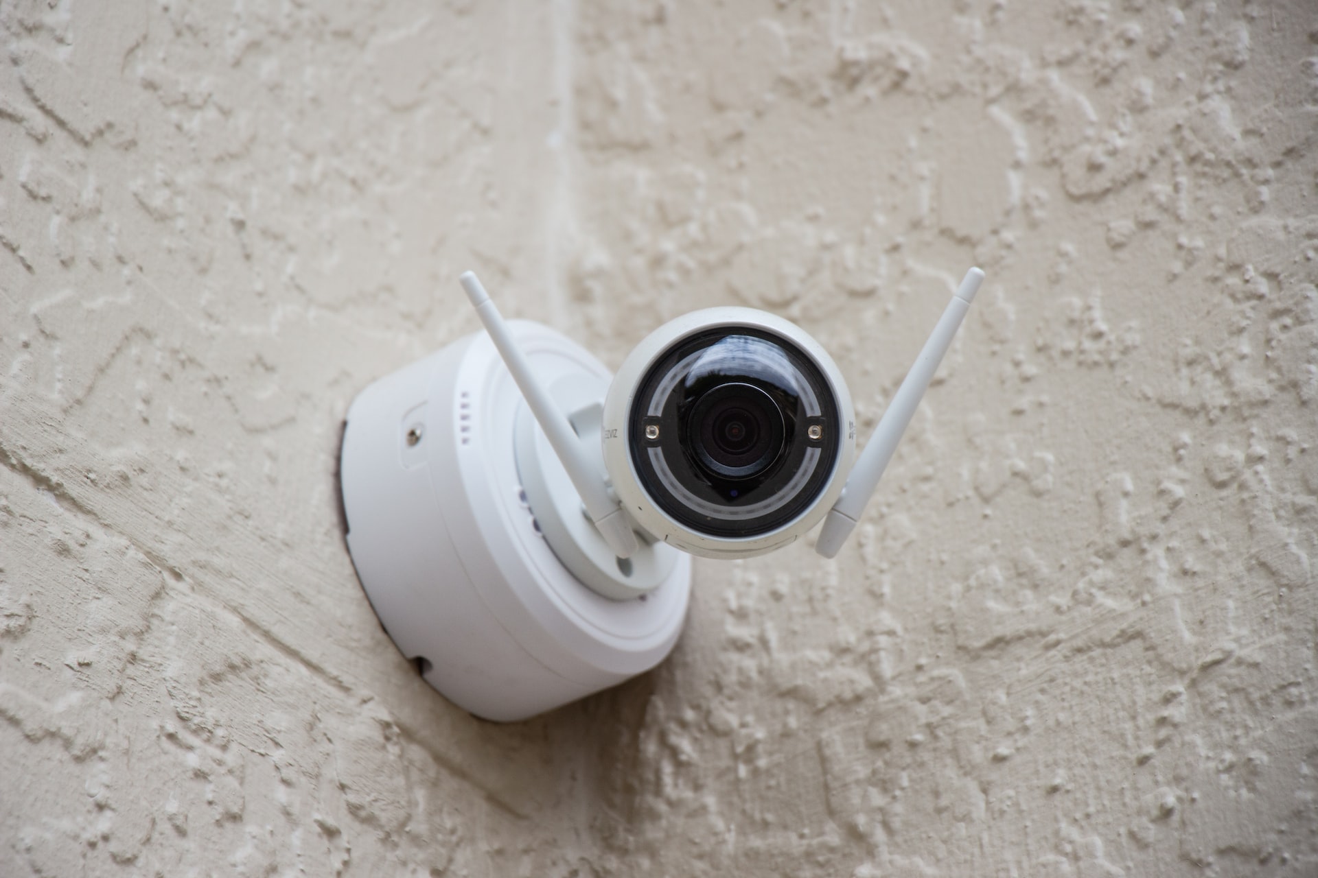 white surveillance camera hanging on wall